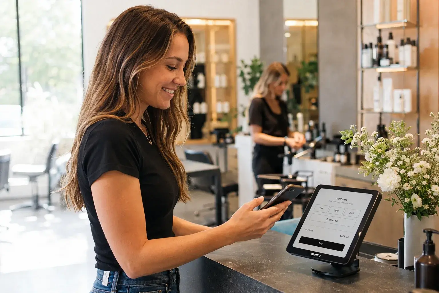 A happy salon client using a smartphone at the front desk